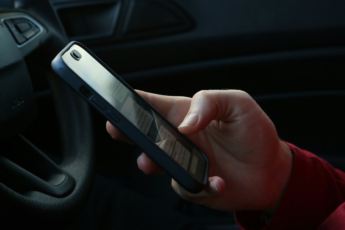 Mão segurando um smartphone dentro de um carro